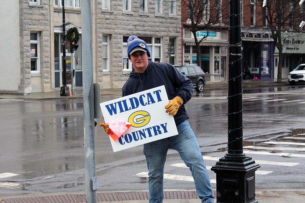 hs student trying to sell wildcat country signs at the winter carnival