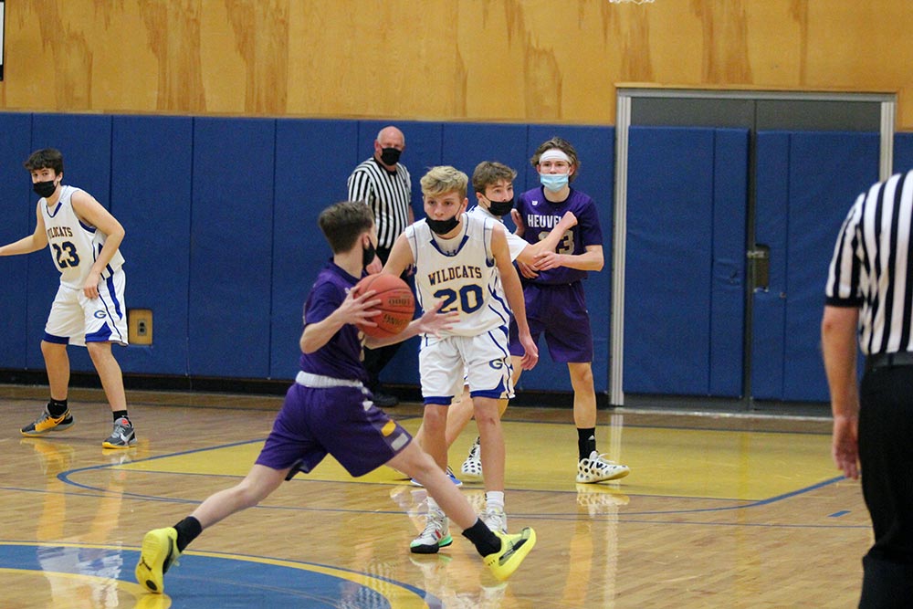 jv boy basketball player defending the circle from a heuvelton player