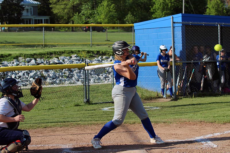 jv softball batter in midswing ball in view at edge of photo