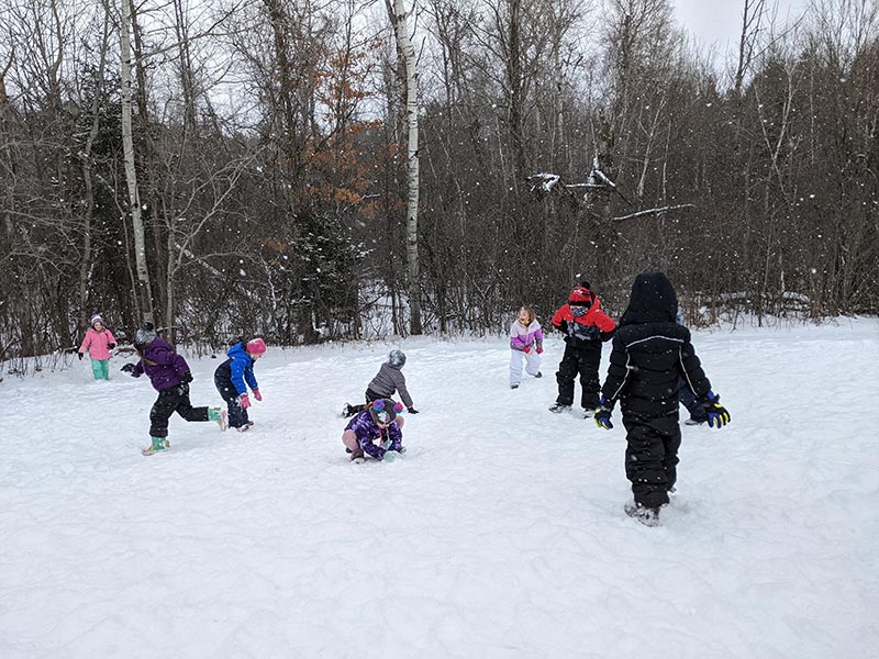 elementary students in snow gear playing in the snow