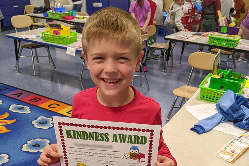 male student holding a kindness award