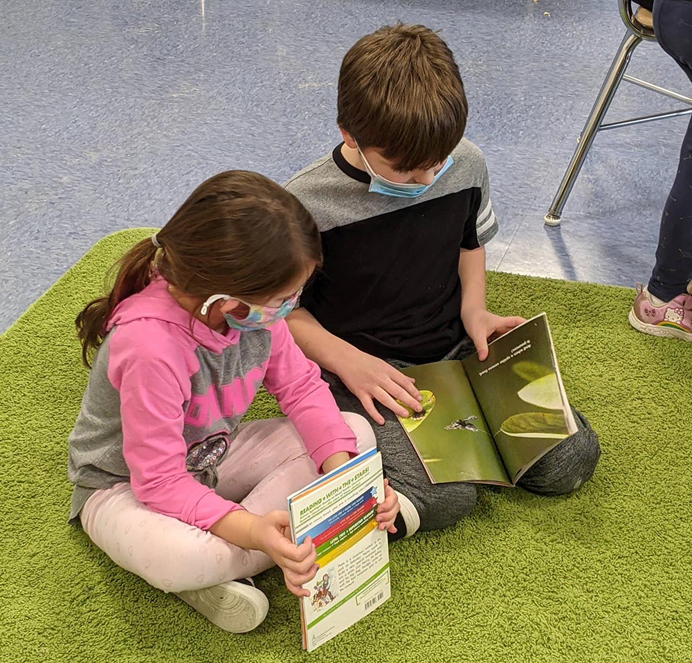 young female and male student reading together on a carpet