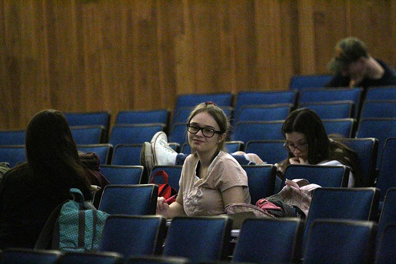 High school girl sitting in auditorium seat smiling at camera